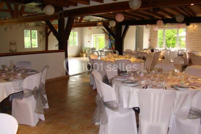 Arche de cérémonie décorée de fleurs blanches et de voilages verts, installée dans un jardin ombragé.