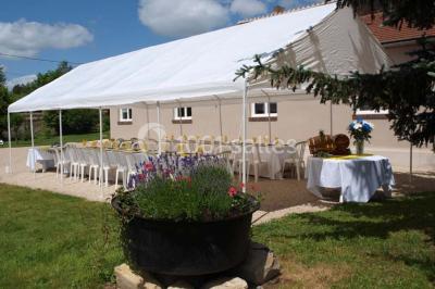Arche de cérémonie décorée de fleurs blanches et de voilages verts, installée dans un jardin ombragé.