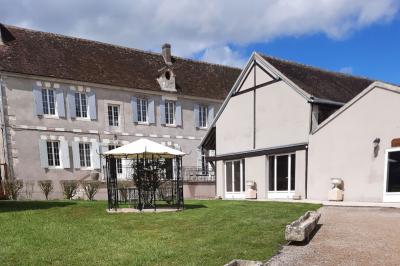 Arche de cérémonie décorée de fleurs blanches et de voilages verts, installée dans un jardin ombragé.