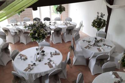 Arche de cérémonie décorée de fleurs blanches et de voilages verts, installée dans un jardin ombragé.