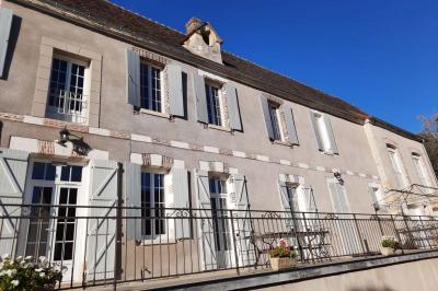 Arche de cérémonie décorée de fleurs blanches et de voilages verts, installée dans un jardin ombragé.