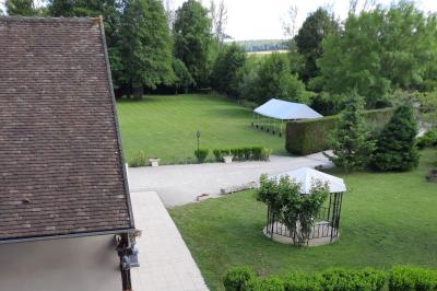 Arche de cérémonie décorée de fleurs blanches et de voilages verts, installée dans un jardin ombragé.