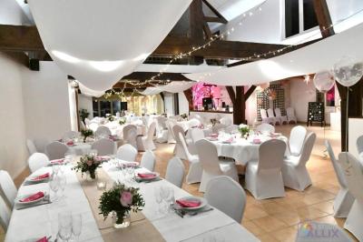 Arche de cérémonie décorée de fleurs blanches et de voilages verts, installée dans un jardin ombragé.