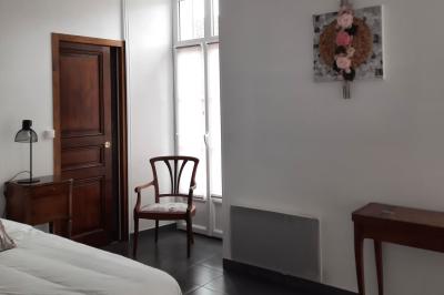 Arche de cérémonie décorée de fleurs blanches et de voilages verts, installée dans un jardin ombragé.