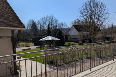 Arche de cérémonie décorée de fleurs blanches et de voilages verts, installée dans un jardin ombragé.