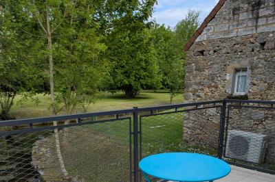 Arche de cérémonie décorée de fleurs blanches et de voilages verts, installée dans un jardin ombragé.