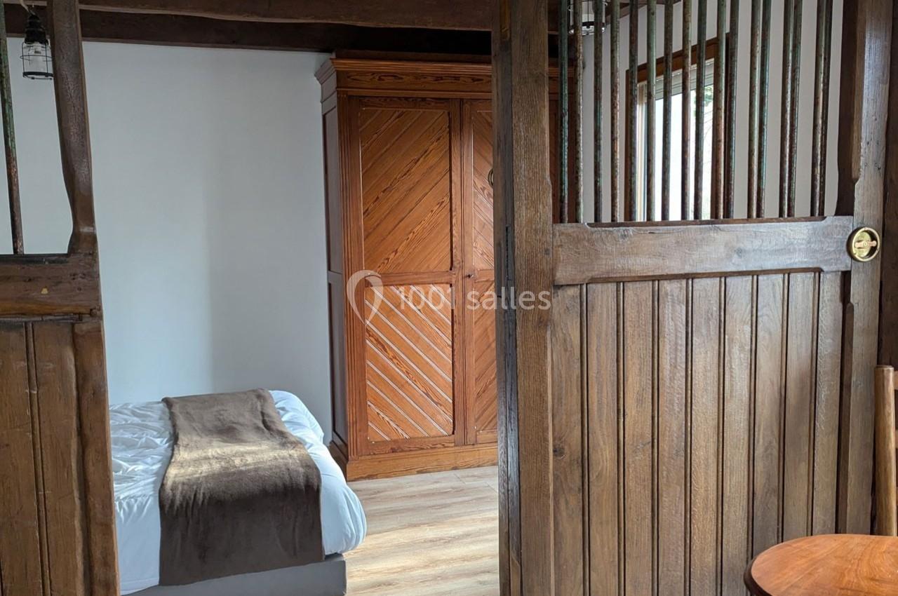 Vue d'une chambre avec un lit simple, une armoire en bois et des éléments de séparation en bois.