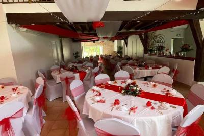 Arche de cérémonie décorée de fleurs blanches et de voilages verts, installée dans un jardin ombragé.