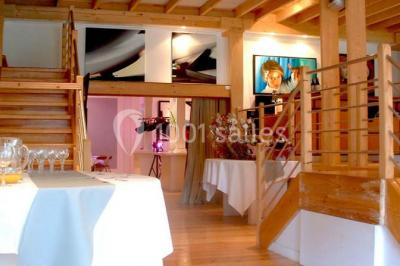 Terrasse en bois longeant un bâtiment en briques avec vue sur un jardin arboré sous un ciel bleu.