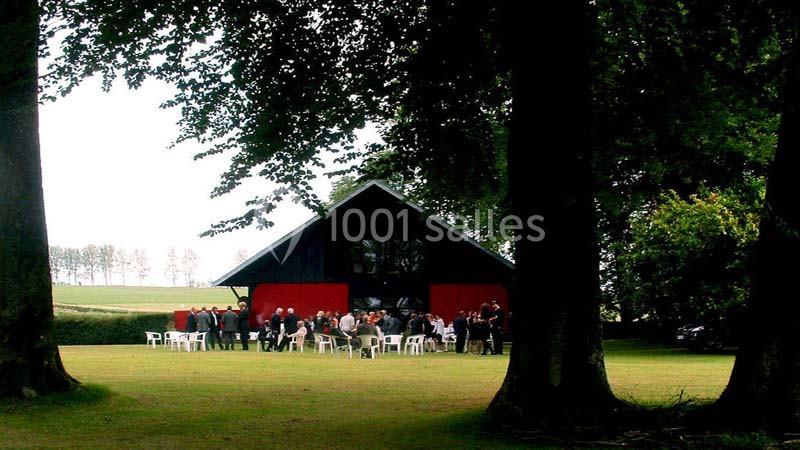 Groupe de personnes rassemblées devant un bâtiment noir et rouge dans un espace vert entouré d'arbres.