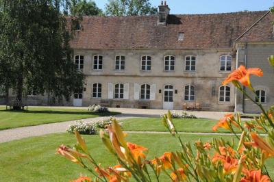 Cour enneigée avec bâtiments en pierre, un pigeonnier cylindrique et des arbres nus sous un ciel dégagé.