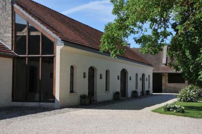 Cour enneigée avec bâtiments en pierre, un pigeonnier cylindrique et des arbres nus sous un ciel dégagé.