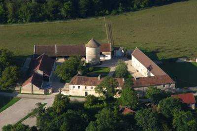 Cour enneigée avec bâtiments en pierre, un pigeonnier cylindrique et des arbres nus sous un ciel dégagé.