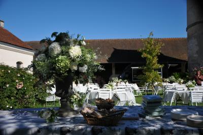Cour enneigée avec bâtiments en pierre, un pigeonnier cylindrique et des arbres nus sous un ciel dégagé.