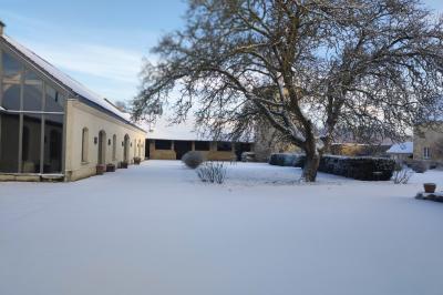 Cour enneigée avec bâtiments en pierre, un pigeonnier cylindrique et des arbres nus sous un ciel dégagé.