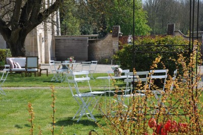 Cour enneigée avec bâtiments en pierre, un pigeonnier cylindrique et des arbres nus sous un ciel dégagé.