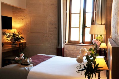 Cour enneigée avec bâtiments en pierre, un pigeonnier cylindrique et des arbres nus sous un ciel dégagé.