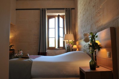 Cour enneigée avec bâtiments en pierre, un pigeonnier cylindrique et des arbres nus sous un ciel dégagé.