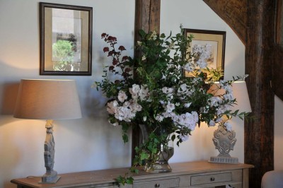 Cour enneigée avec bâtiments en pierre, un pigeonnier cylindrique et des arbres nus sous un ciel dégagé.