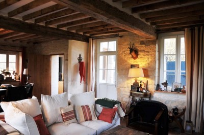 Cour enneigée avec bâtiments en pierre, un pigeonnier cylindrique et des arbres nus sous un ciel dégagé.