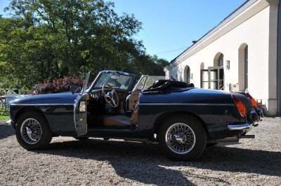 Cour enneigée avec bâtiments en pierre, un pigeonnier cylindrique et des arbres nus sous un ciel dégagé.