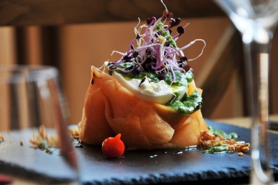 Cour enneigée avec bâtiments en pierre, un pigeonnier cylindrique et des arbres nus sous un ciel dégagé.