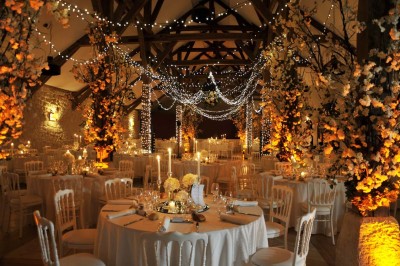 Cour enneigée avec bâtiments en pierre, un pigeonnier cylindrique et des arbres nus sous un ciel dégagé.
