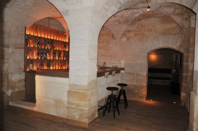 Cour enneigée avec bâtiments en pierre, un pigeonnier cylindrique et des arbres nus sous un ciel dégagé.