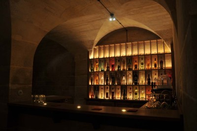 Cour enneigée avec bâtiments en pierre, un pigeonnier cylindrique et des arbres nus sous un ciel dégagé.