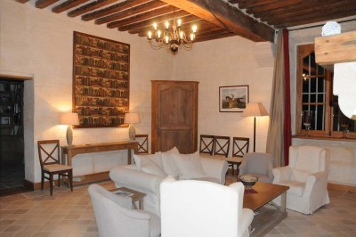 Cour enneigée avec bâtiments en pierre, un pigeonnier cylindrique et des arbres nus sous un ciel dégagé.