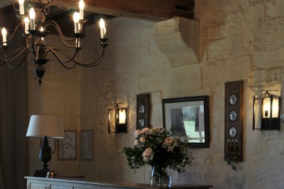 Cour enneigée avec bâtiments en pierre, un pigeonnier cylindrique et des arbres nus sous un ciel dégagé.