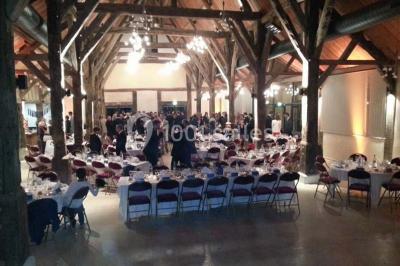 Salle de réception avec rangées de chaises rouges alignées sous une charpente en bois apparente.