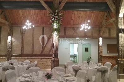 Salle de réception avec rangées de chaises rouges alignées sous une charpente en bois apparente.