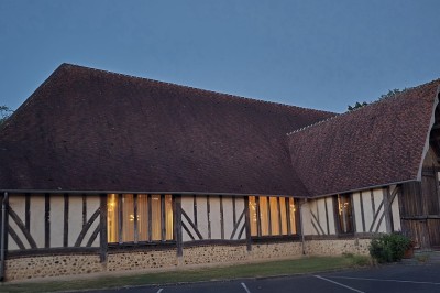 Miniature Location salle La Ferté-Frênel (Orne) - La Grange de Villeron #21 Charpente en bois apparente dans une grande salle lumineuse avec murs en pierre et écran blanc au fond.