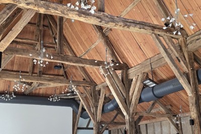 Miniature Location salle La Ferté-Frênel (Orne) - La Grange de Villeron #25 Charpente en bois apparente dans une grande salle lumineuse avec murs en pierre et écran blanc au fond.