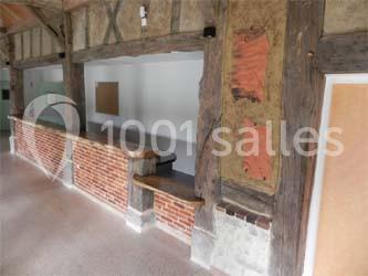 Mur intérieur avec poutres en bois apparentes, briques rouges et un comptoir intégré dans un espace lumineux.