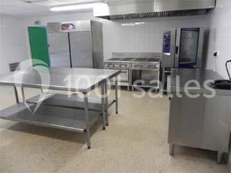 Cuisine professionnelle équipée avec des plans de travail en inox, des réfrigérateurs et des appareils de cuisson.