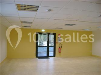 Salle de réception avec rangées de chaises rouges alignées sous une charpente en bois apparente.