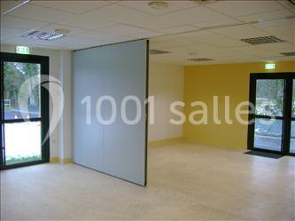 Salle lumineuse avec cloison mobile, murs jaunes et blancs, sol clair, et portes vitrées donnant sur l'extérieur.