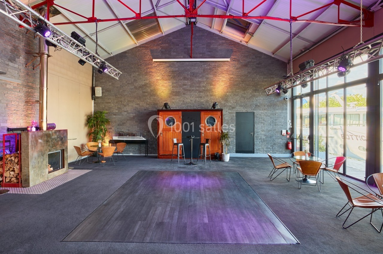 Location salle Paris 15 (Paris) - Paris Yacht Marina #5 Salle spacieuse avec parquet central, murs en pierre, mobilier moderne et éclairage coloré, ambiance industrielle.