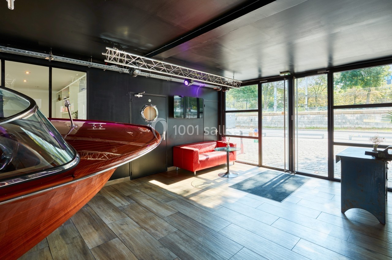 Location salle Paris 15 (Paris) - Paris Yacht Marina #19 Intérieur lumineux avec un bateau en bois, un canapé rouge et de grandes baies vitrées donnant sur l'extérieur.