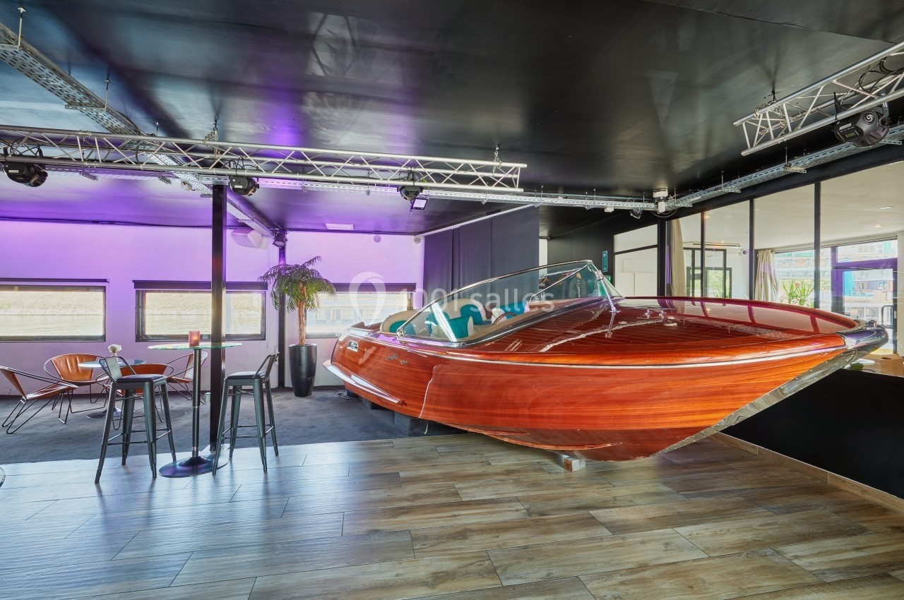 Location salle Paris 15 (Paris) - Paris Yacht Marina #6 Bateau en bois verni aménagé en mobilier dans un espace intérieur moderne avec éclairage violet.