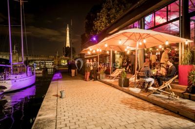 Bateaux amarrés le long d'un quai sur une rivière, avec une promenade bordée d'arbres à gauche.