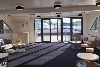 Bateaux amarrés le long d'un quai sur une rivière, avec une promenade bordée d'arbres à gauche.
