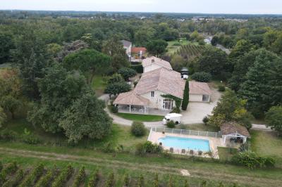 Salle de réception lumineuse avec tables rondes dressées, nappes blanches, chaises en bois et décorations florales.