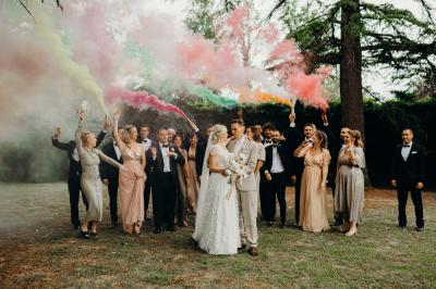Salle de réception lumineuse avec tables rondes dressées, nappes blanches, chaises en bois et décorations florales.