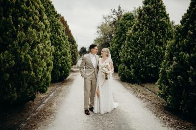 Salle de réception lumineuse avec tables rondes dressées, nappes blanches, chaises en bois et décorations florales.