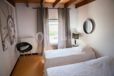 Chambre lumineuse avec un lit double, deux tables de chevet avec lampes allumées et une fenêtre donnant sur un paysage…