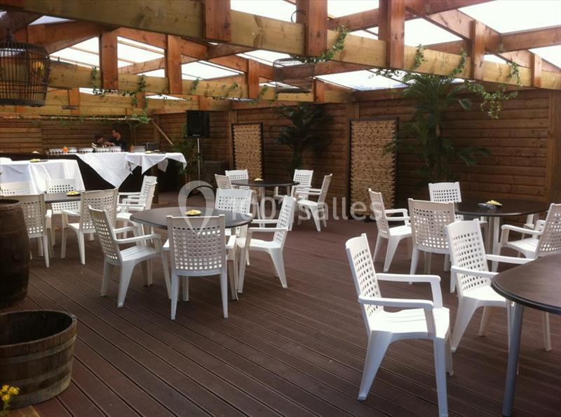 Terrasse couverte avec mobilier en plastique blanc, tables noires et décor en bois, aménagée pour un événement.