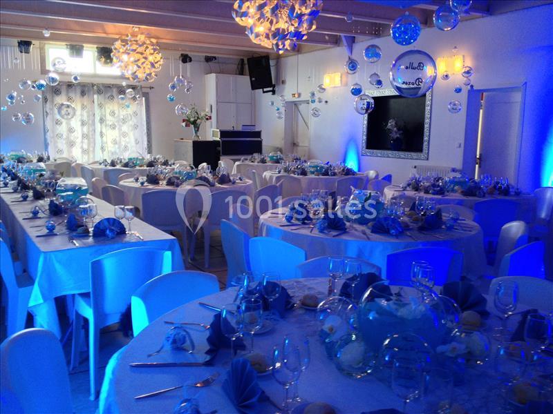 Salle de réception décorée dans des tons bleus avec des tables rondes dressées pour un événement festif.